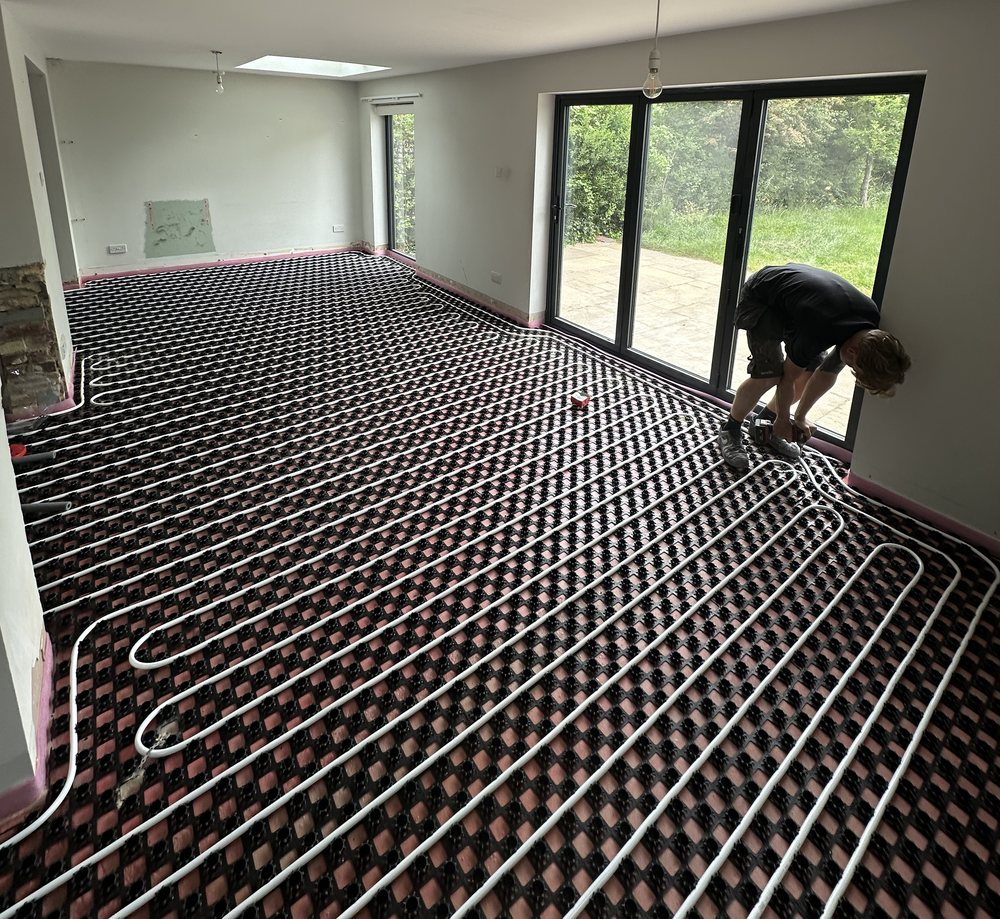 Cambs Heating engineer laying wet underfloor heating pipes in a Cambridge extension